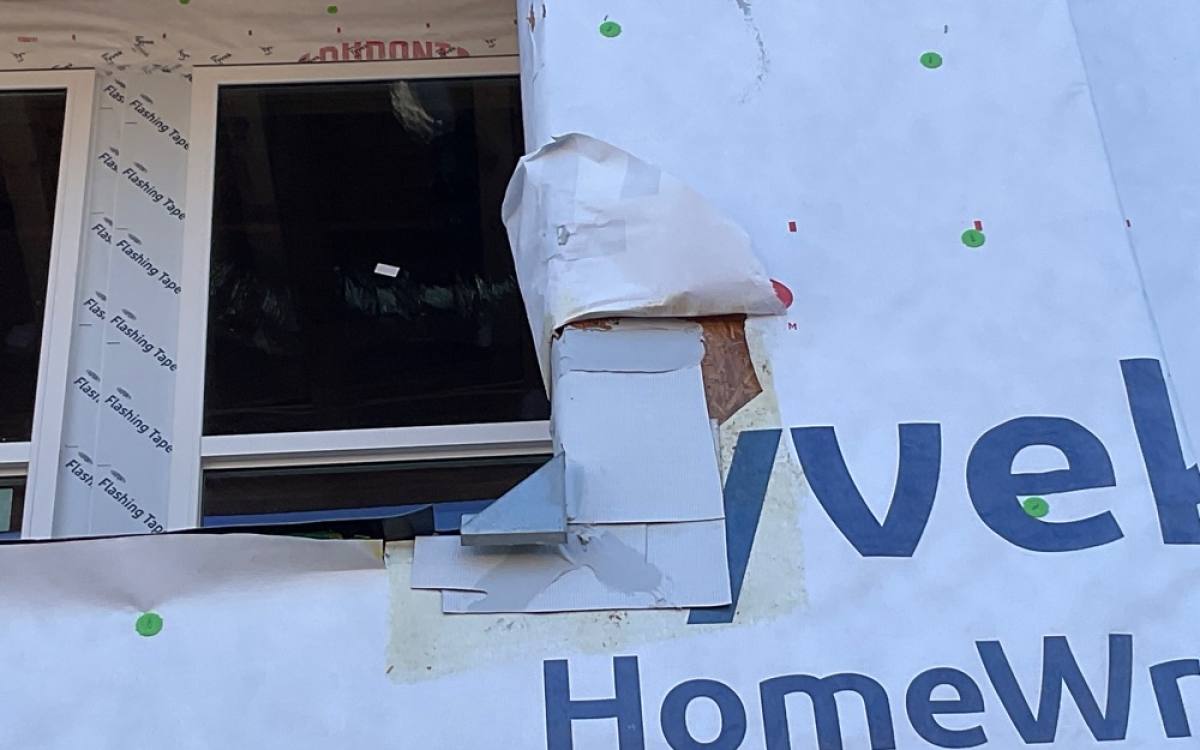 Construction site photo: window with torn housewrap exposing sheathing and loose flashing, annotated by SuperClear AI