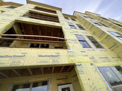 Site photo: low-angle view of a building wrapped in housewrap